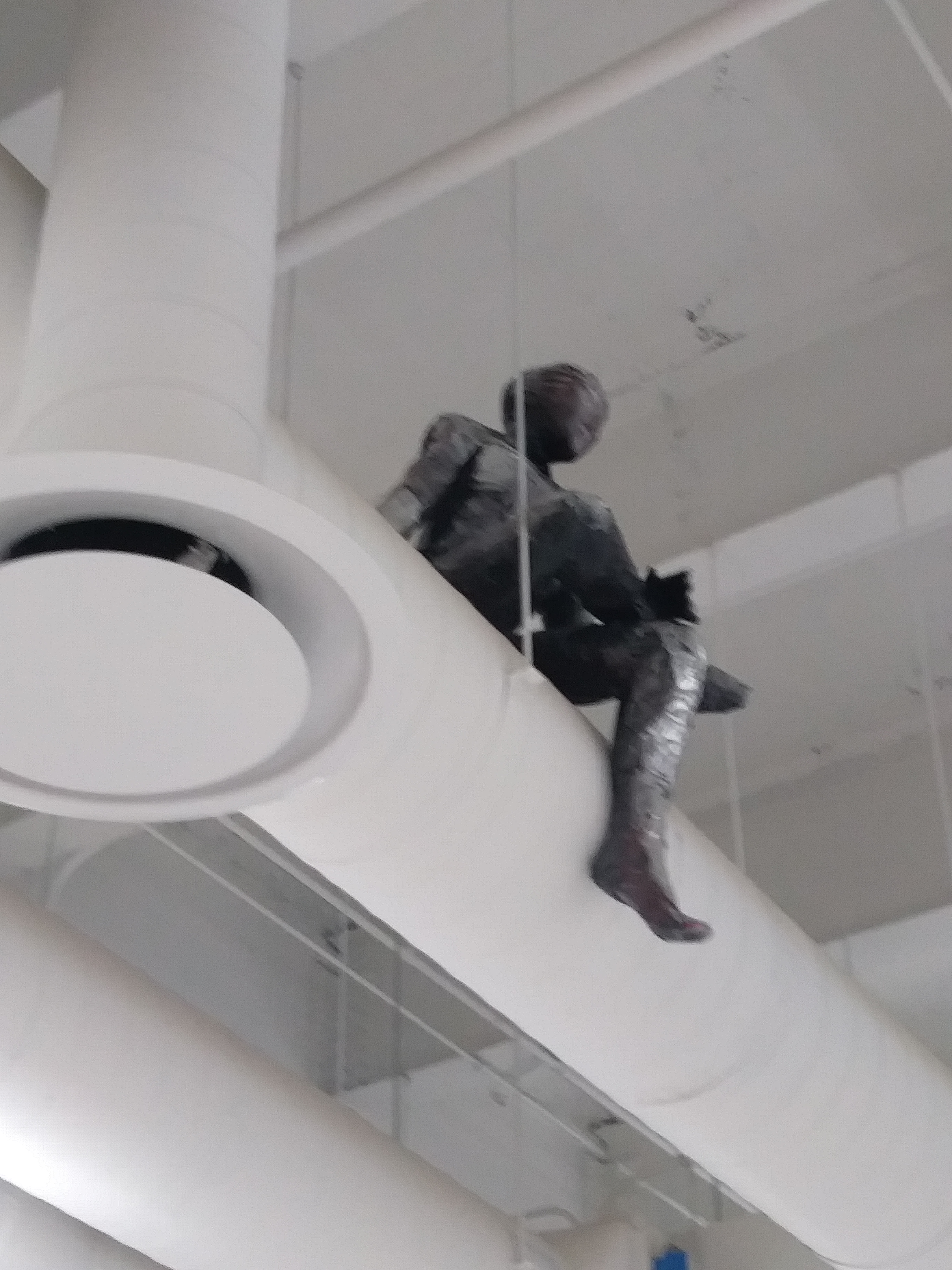 a sculpture made by Ada Denil of a human sitting on a vent in an industrial space