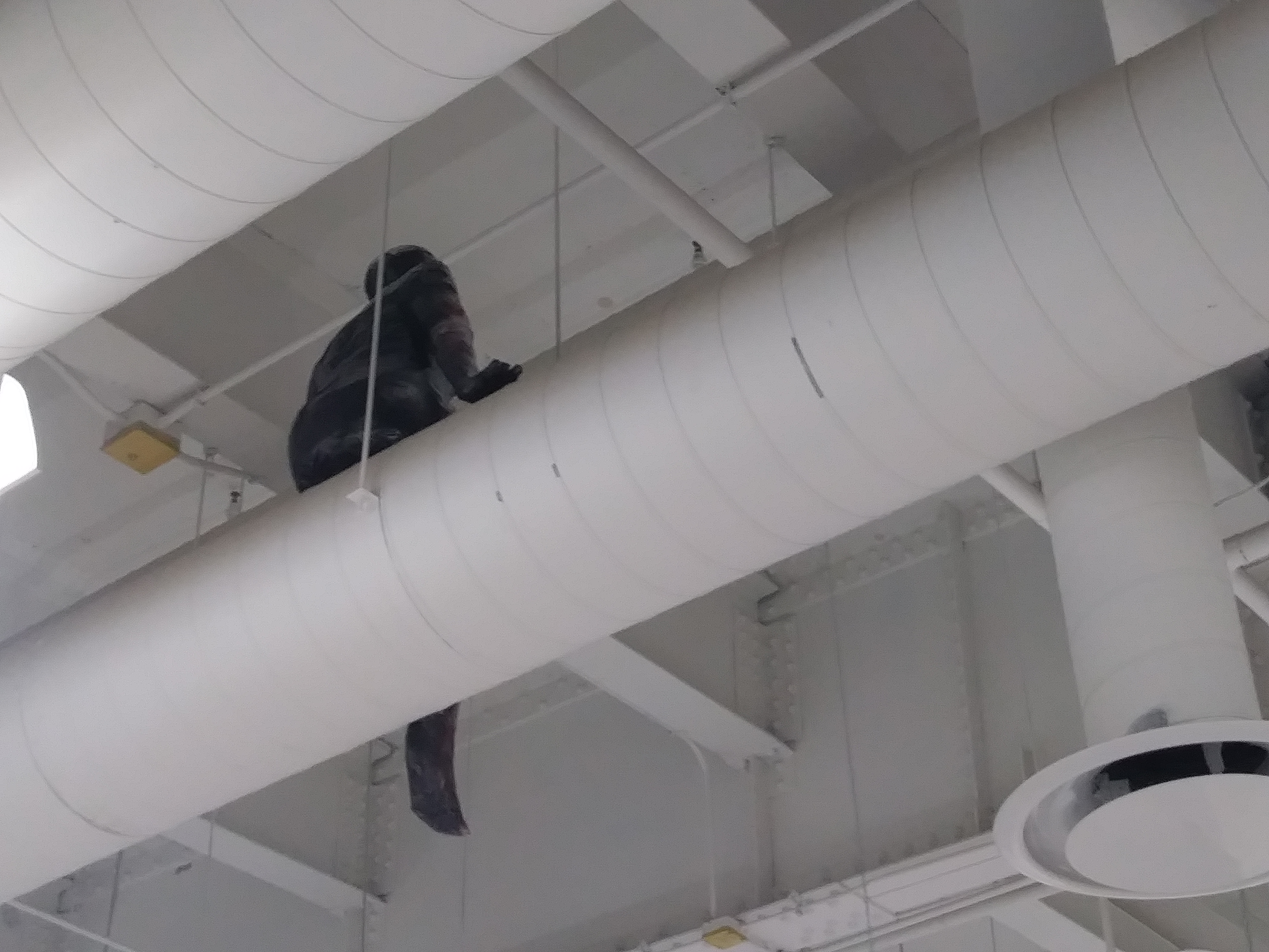 a sculpture made by Ada Denil of a human sitting on a vent in an industrial space