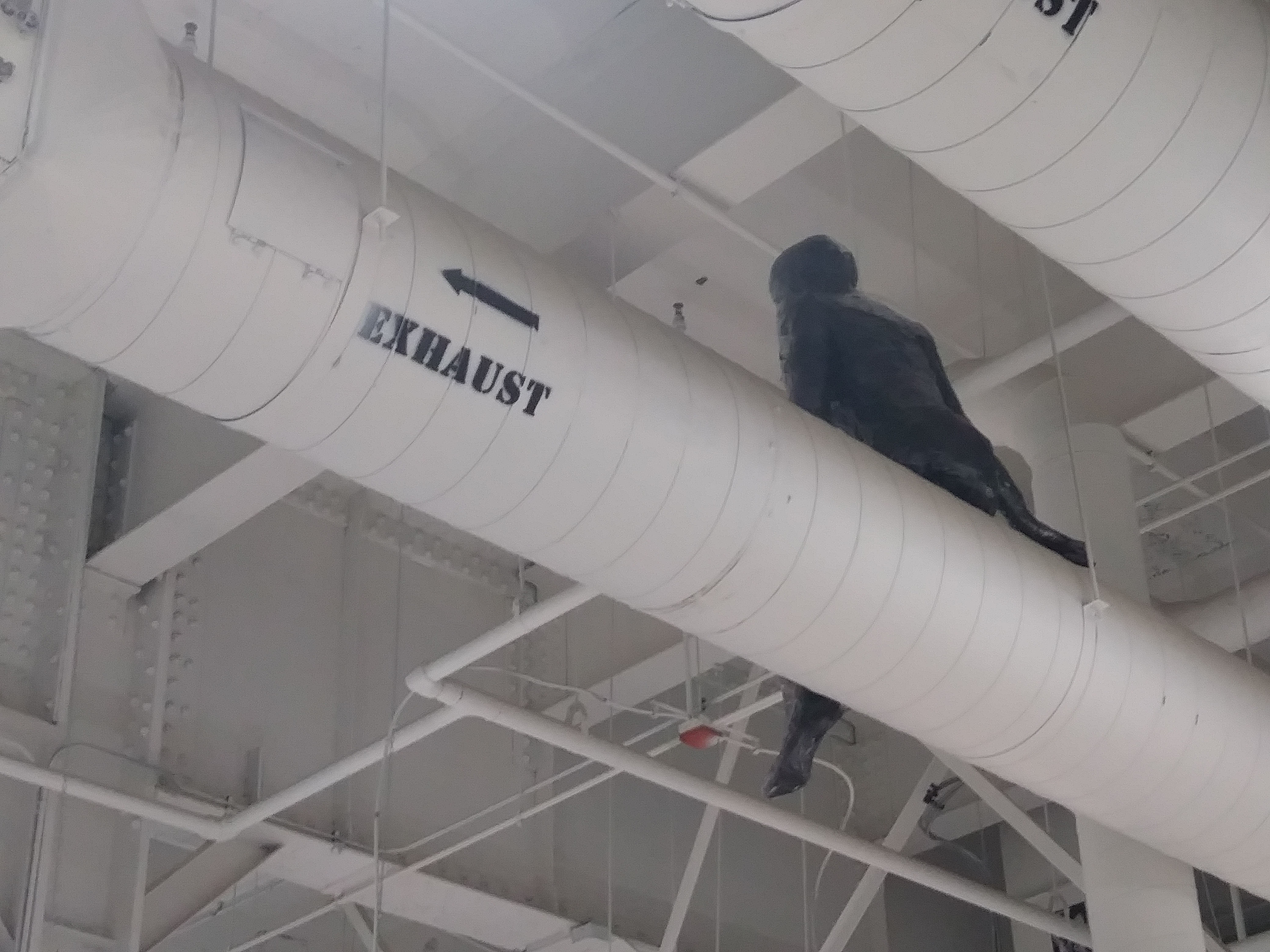 a sculpture made by Ada Denil of a human sitting on a vent in an industrial space